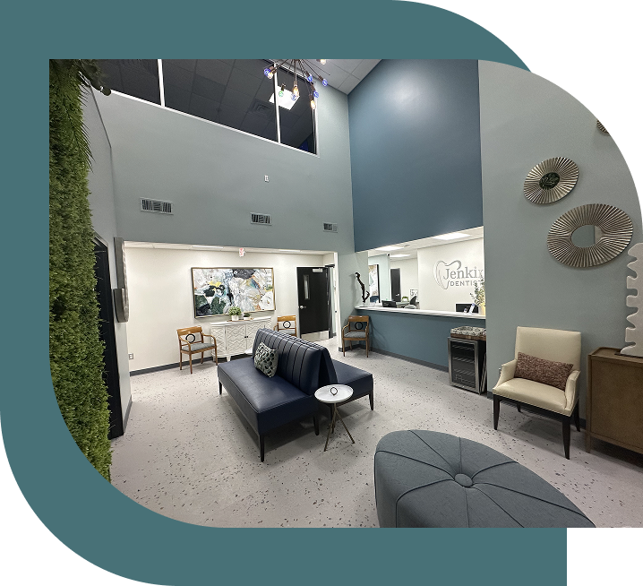 Modern lobby with tall ceilings, featuring a vertical green wall and abstract art. Cozy seating includes beige chairs and a blue sofa, conveying a welcoming atmosphere.