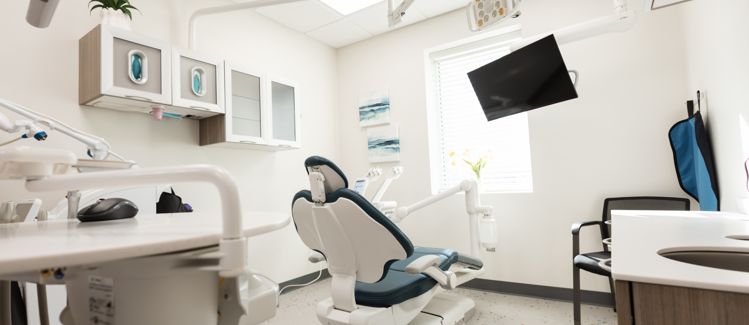 A dental office featuring a patient chair, sink, and mirror, designed for dental examinations and treatments.