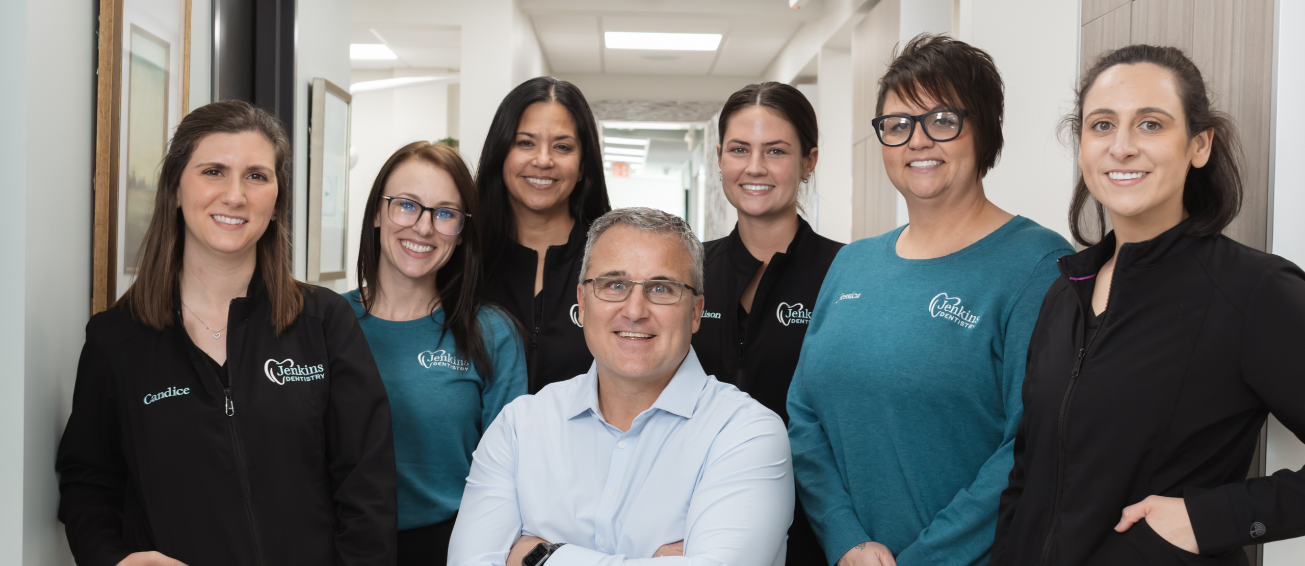 Team members of Jenkins Dentistry pose together, smiling in a bright, welcoming office environment.