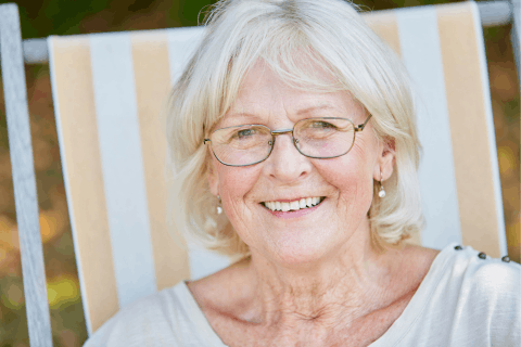 an elderly woman sitting in a chair smiling