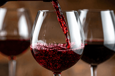a photo of red wine being poured in a wine glass