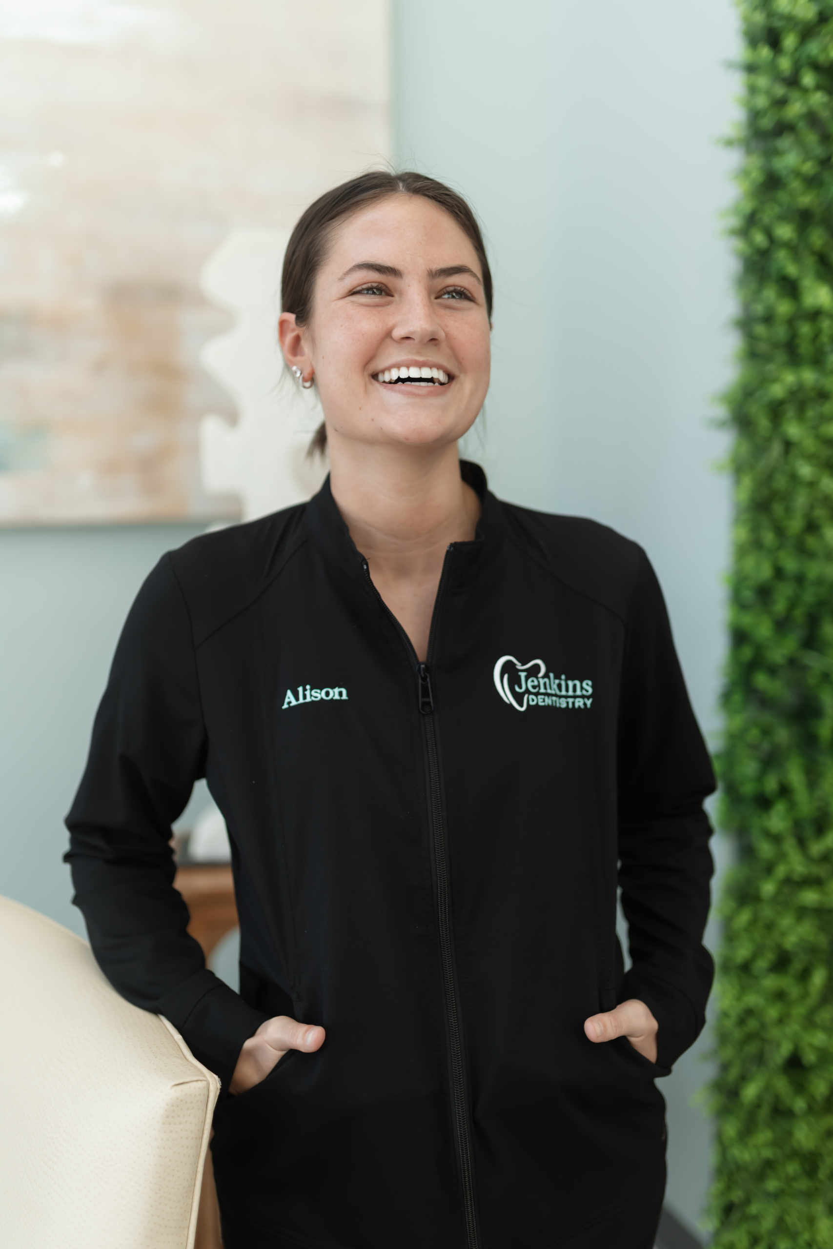 A smiling woman in a black jacket, exuding warmth and positivity.